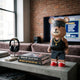 Iron Paw Bear Sculpture (50cm) by Giant Sculptures, styled in a bandana, gold chain, and red hi-tops, displayed on a console table in a living room with books and a TV.