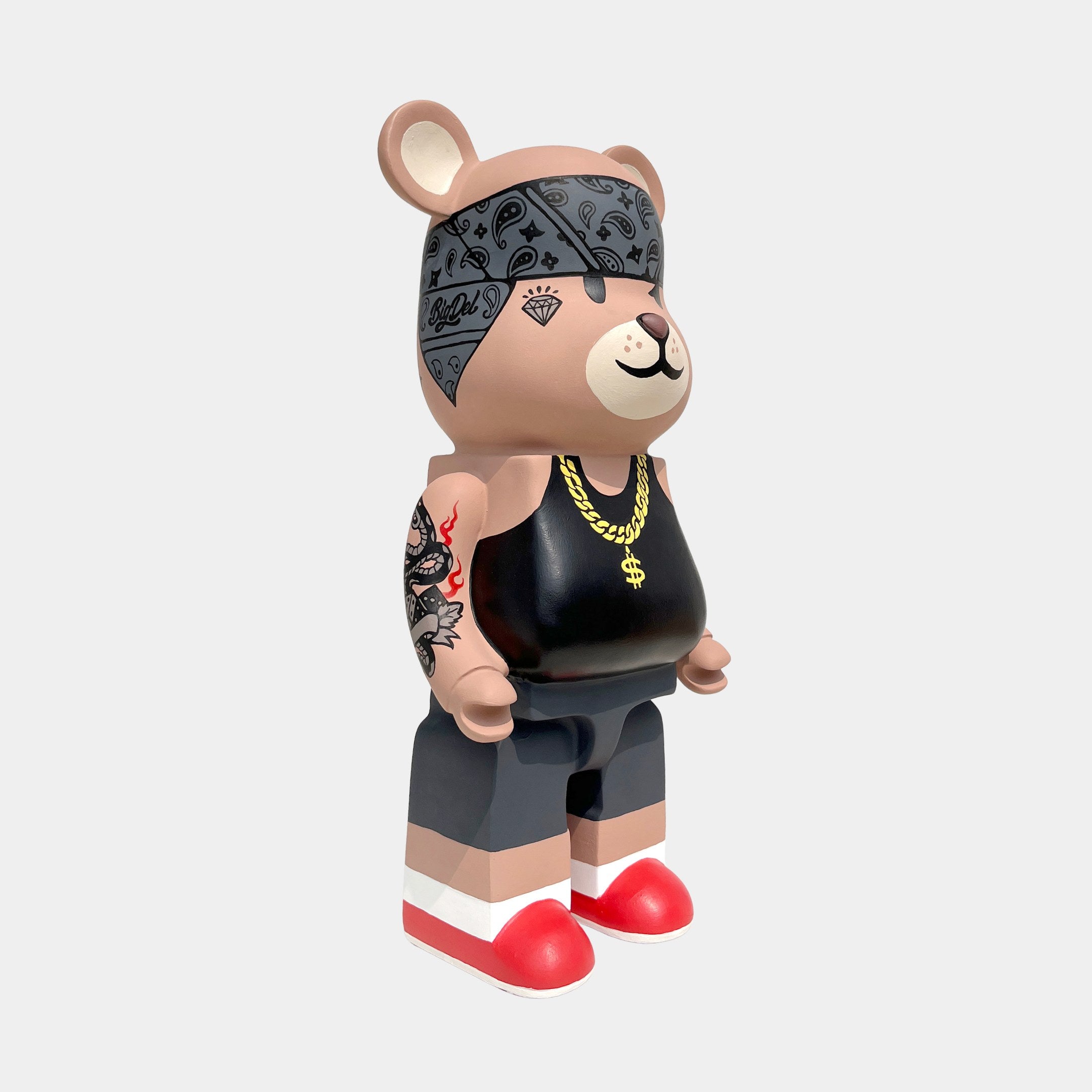 The Iron Paw Bear Sculpture - 50cm by Giant Sculptures is a limited edition street art collectible featuring a toy bear in a black tank top, gold chain, patterned bandana, tattooed arm, gray pants, and red shoes on a white background.