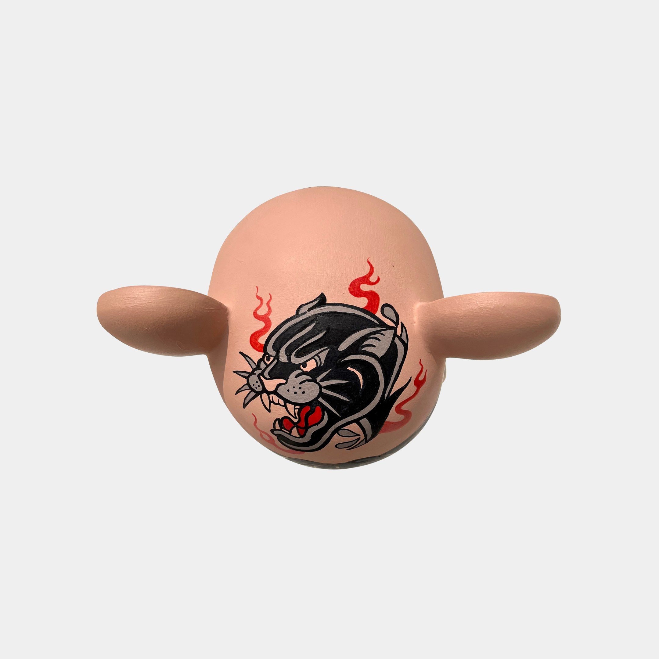 The Iron Paw Bear Sculpture - 50cm by Giant Sculptures features an oval shape with ear-like protrusions, boldly displaying a roaring black panther tattoo surrounded by red flames, making it a striking street art collectible against a plain background.