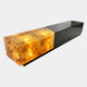 Black & Amber Lit Block Resin Bench, 280cm, matt black rectangular form with an illuminated amber resin end glowing from within, on a plain light background.