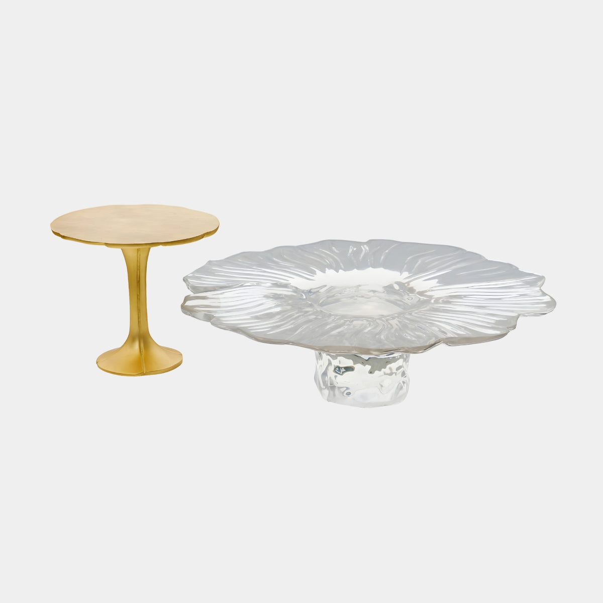 Clear Resin Blossom scalloped petal table beside a Gold Pedestal side table with lobed top, shown on a plain white background.