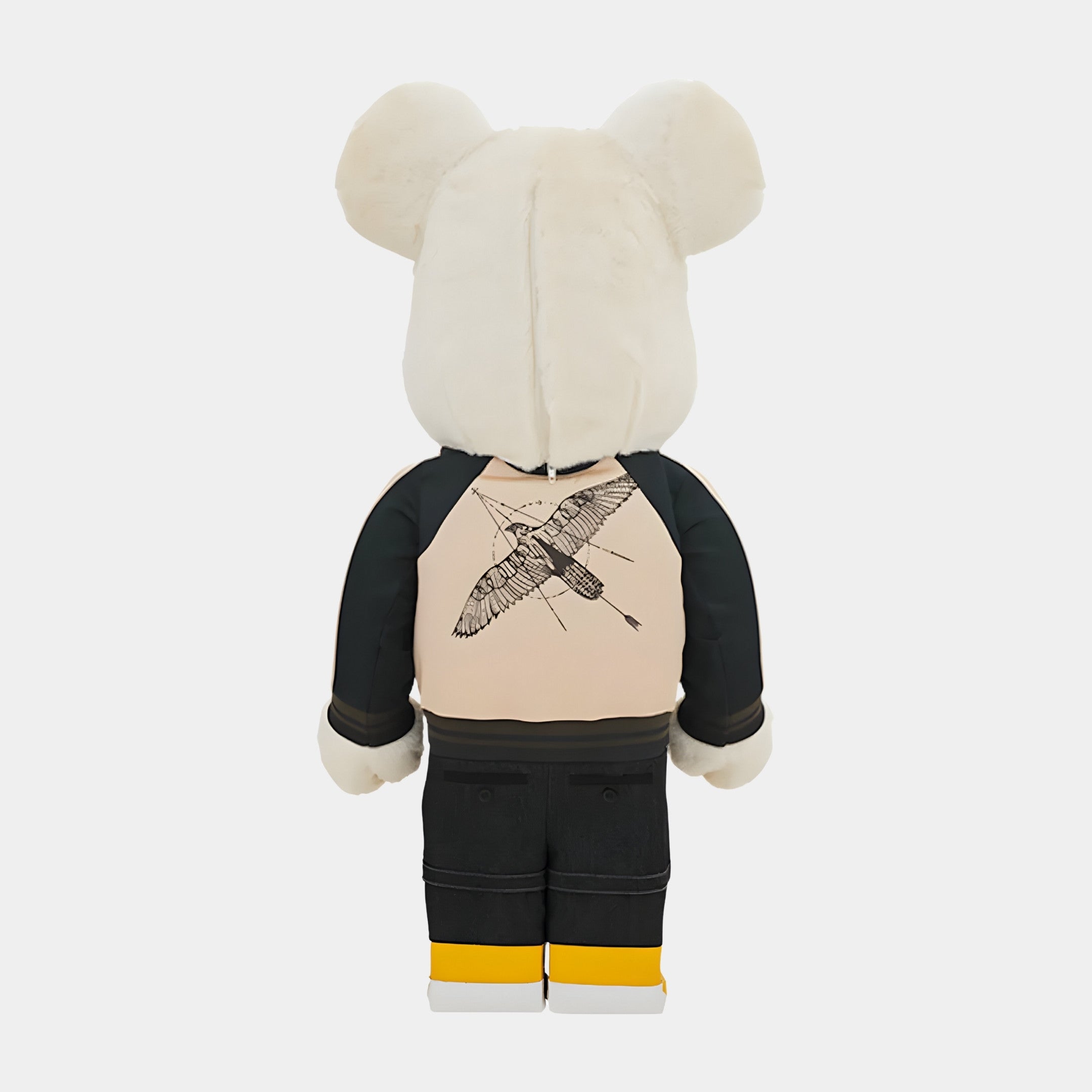 The Jacket Clad Plush Bear Sculpture by Giant Sculptures (70cm) is shown from the back with cream fur, wearing a tan and black streetwear art jacket featuring a crane, black pants, and yellow-white shoes.