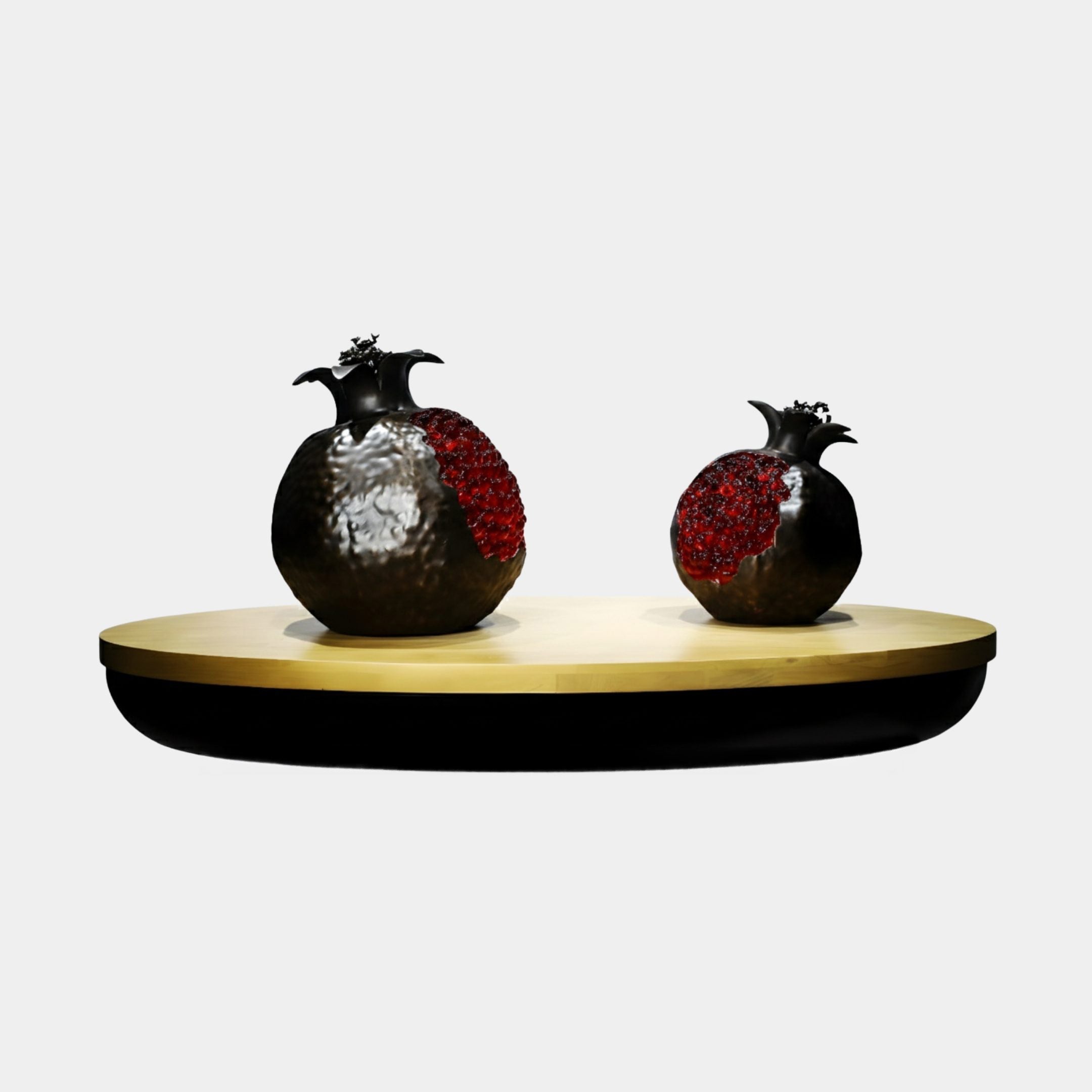 Black & Red Pomegranate Pair on Gold Tray by Giant Sculptures, showing two split pomegranate sculptures with dark bronze shells and red seeds on an oval gold tray.