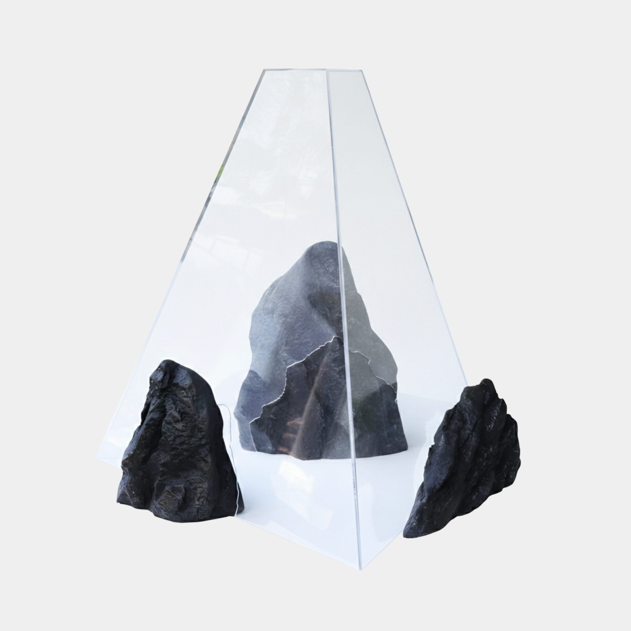 Charcoal Black Pyramid Enclosed Rock Resin Sculpture by Giant Sculptures, clear faceted pyramid encasing a grey rock with two smaller stones beside it.
