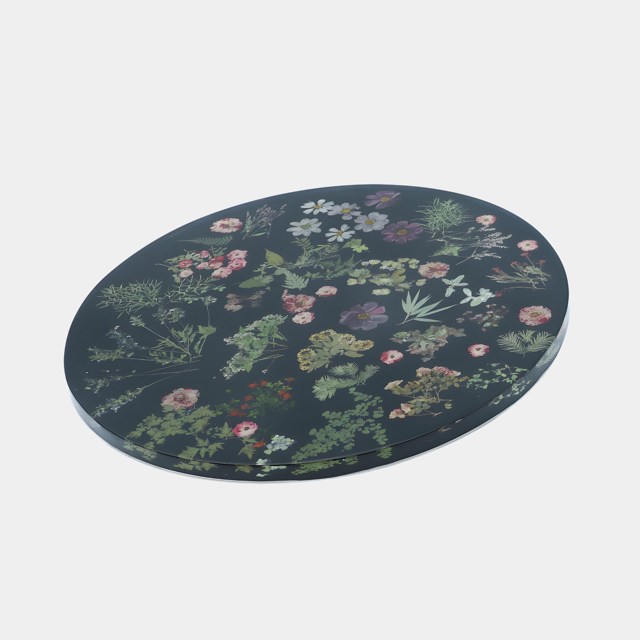 Black Floral Disc Panel Sculpture by Giant Sculptures, an 80cm round dark resin panel set with pressed pink, white and green botanicals, on a plain background.