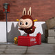 The Hidden Kiddie Ride Labubu Sculpture - 100cm by Giant Sculptures features a coin-operated cartoon bunny with a furry brown suit, large eyes, and wind-up key on a red LABUBU RIDE base—perfect for indoor display.