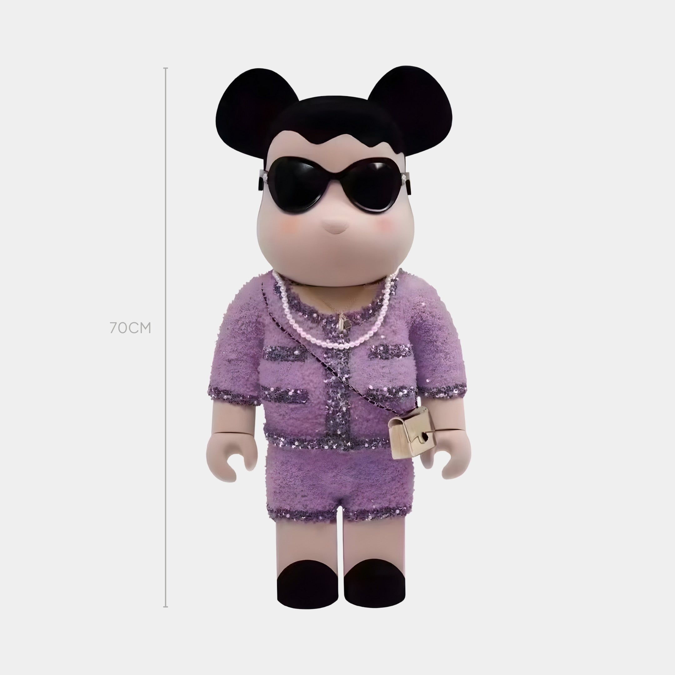 The Lilac Couture Bear Sculpture - 70cm by Giant Sculptures features mouse ears, black sunglasses, a hand-stitched bouclé purple suit with pearl necklaces, and a beige purse. This collectible art piece stands against a plain white background.