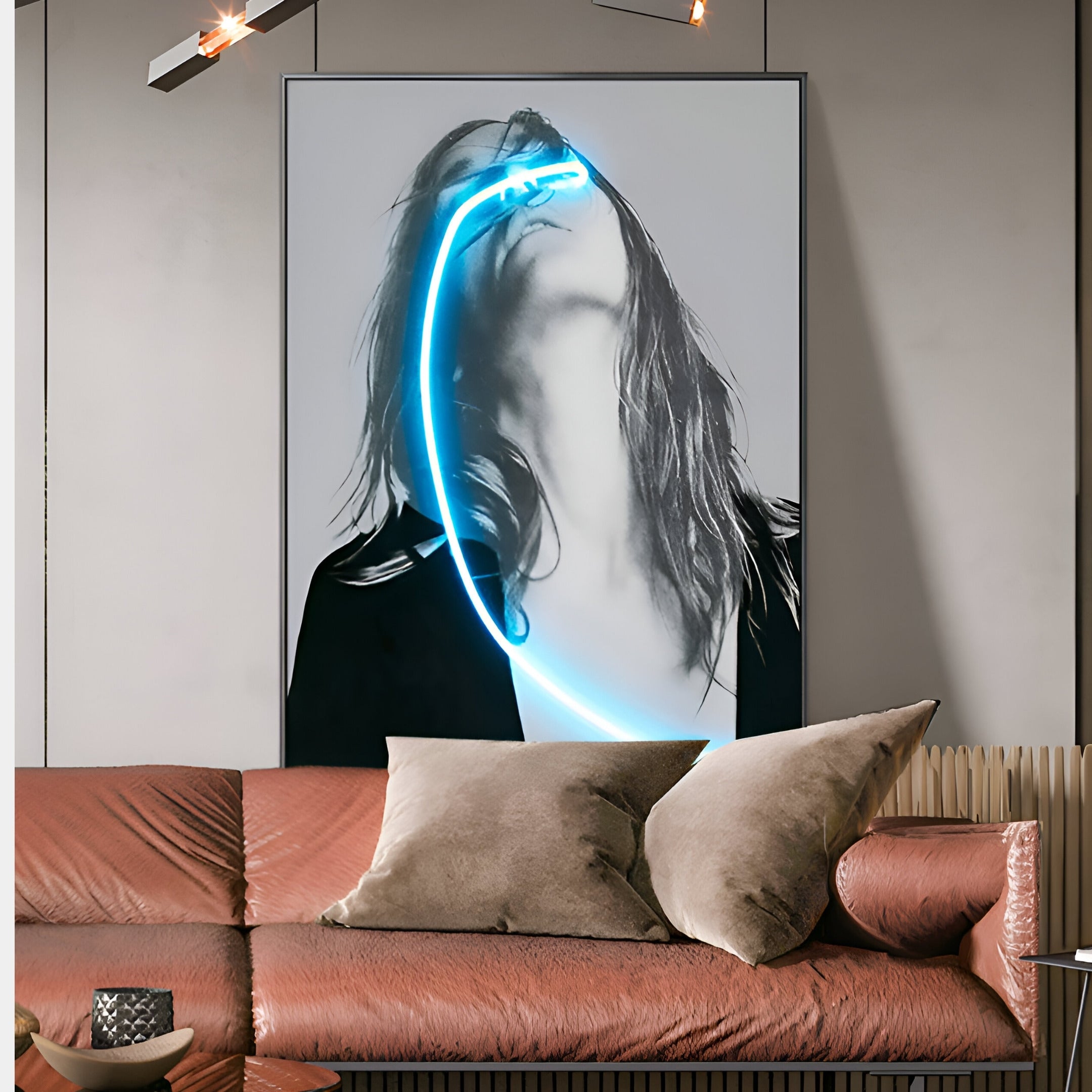 In a modern living room, the Elysian Veiled Grace 3D LED Wall Art by Giant Sculptures is showcased. It features a person tilted back with long hair and a blue neon curve, hanging above a brown leather sofa accented with brown pillows and illuminated by sleek, angled lights to enhance the contemporary design.