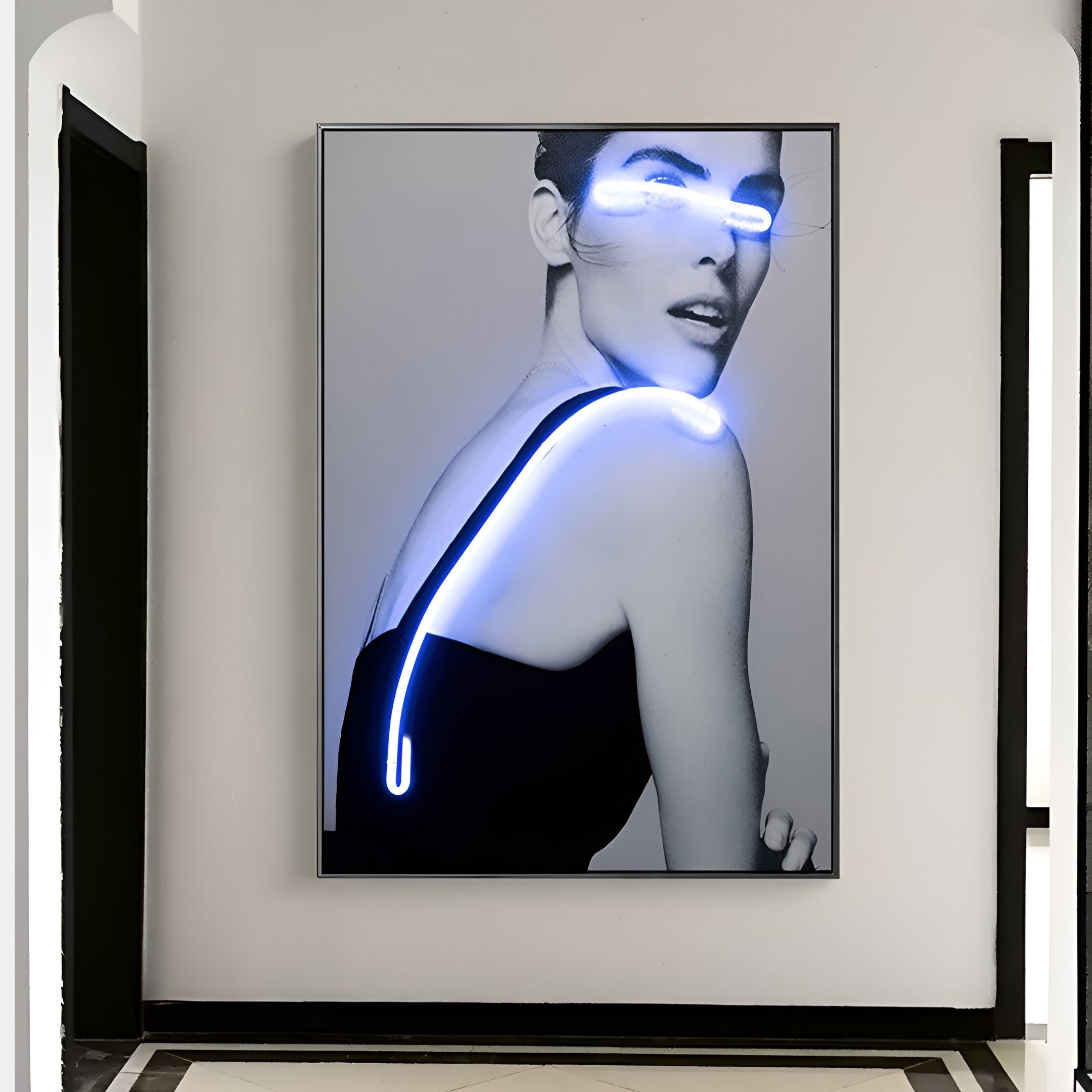 The Elysian Luminescent Gaze 3D LED Wall Art by Giant Sculptures showcases a black and white portrait of a woman in a sleeveless black top with neon lights tracing over her shoulder and eyes, blending modern aesthetics with premium craftsmanship. Its elegantly framed on a pristine white wall.