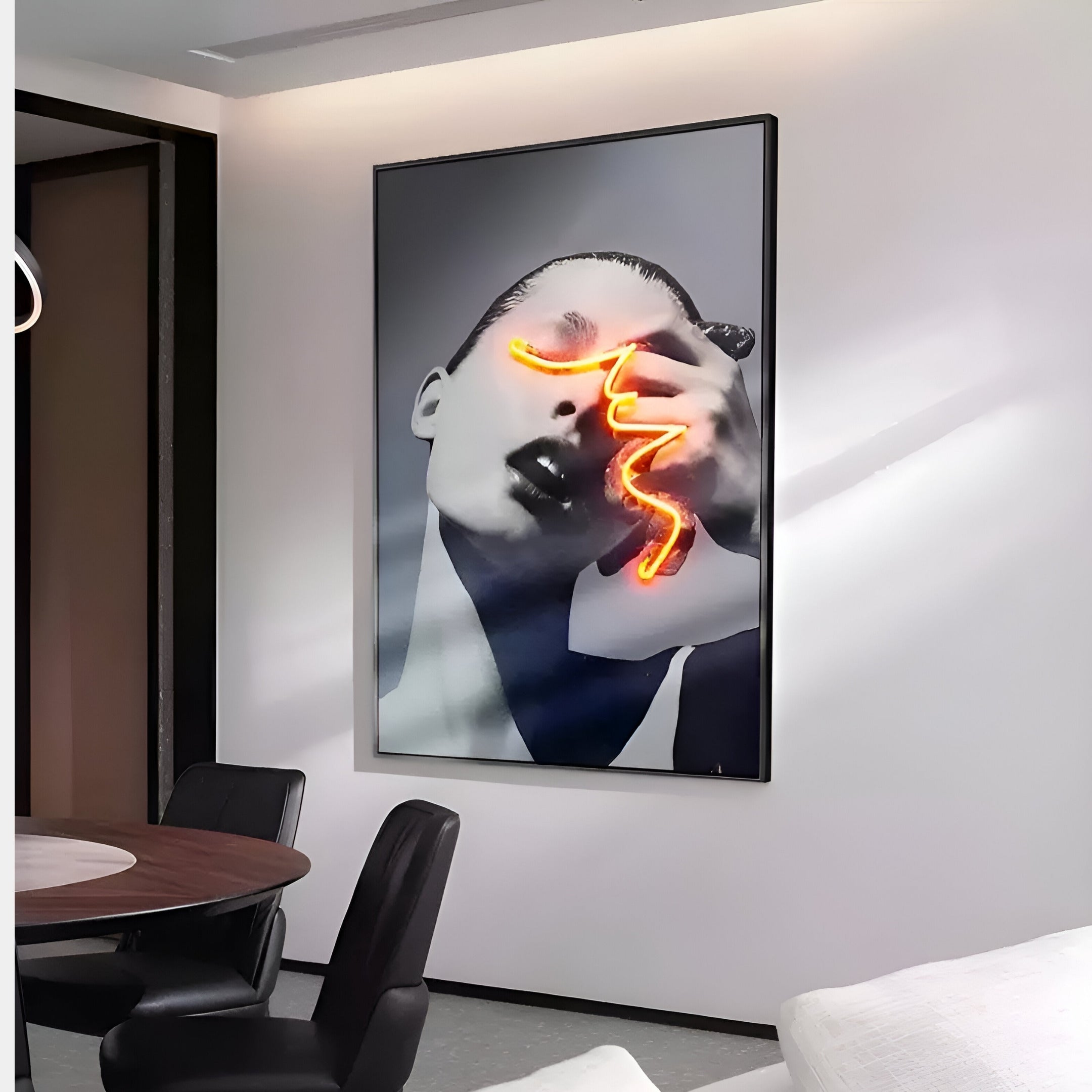 In a modern interior, the Elysian Vibrant Contour 3D LED Wall Art by Giant Sculptures showcases a large black and white portrait with a glowing gaze traced by orange neon light. This captivating piece complements black chairs and a wooden table, creating an alluring blend of modern décor.