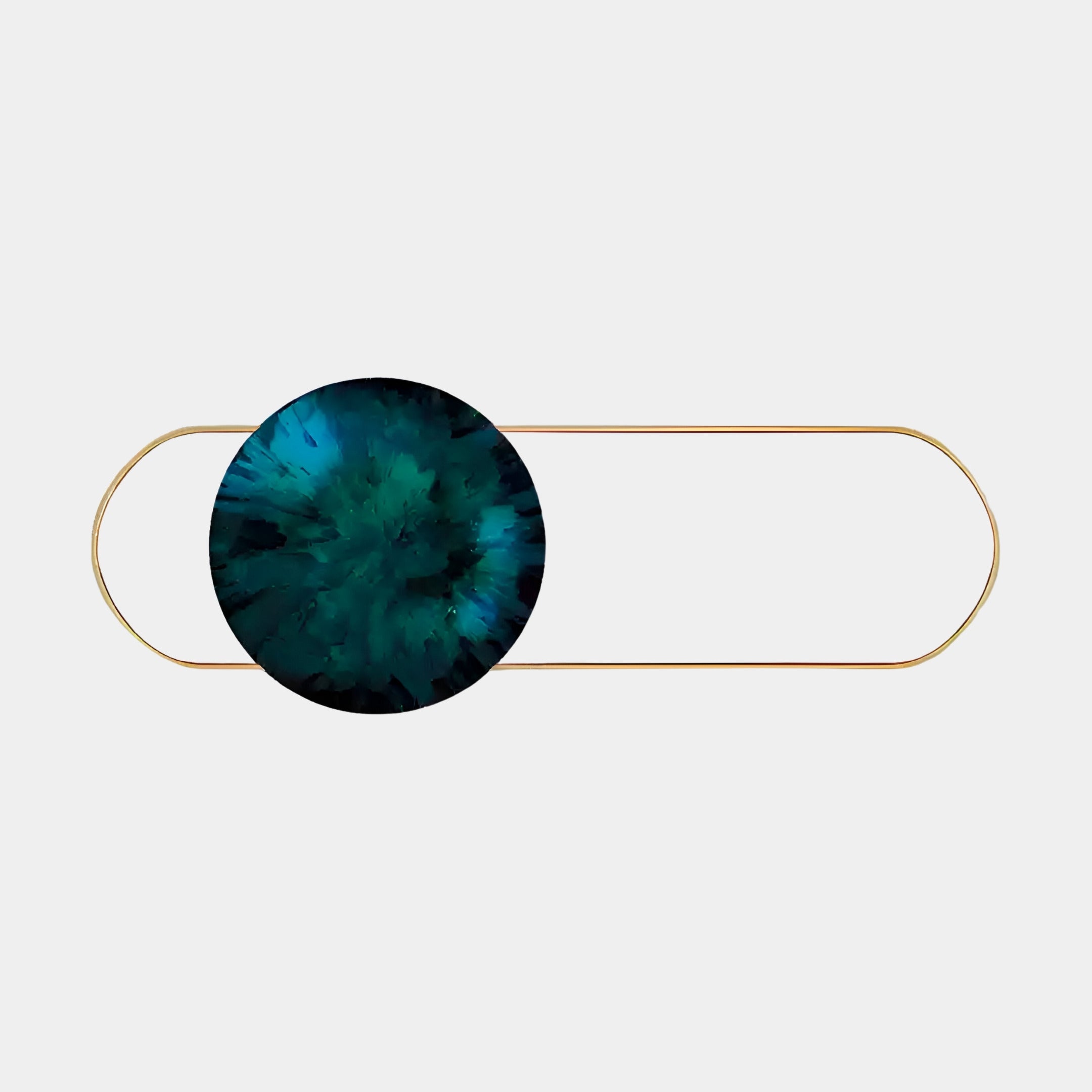 A decorative hairpin with a circular end features a swirling blue and green design, reminiscent of Giant Sculptures Vitreon Deep Green Flat Crystal Porcelain Wall Art. The elongated gold pin balances the vibrant circle against the plain white background.