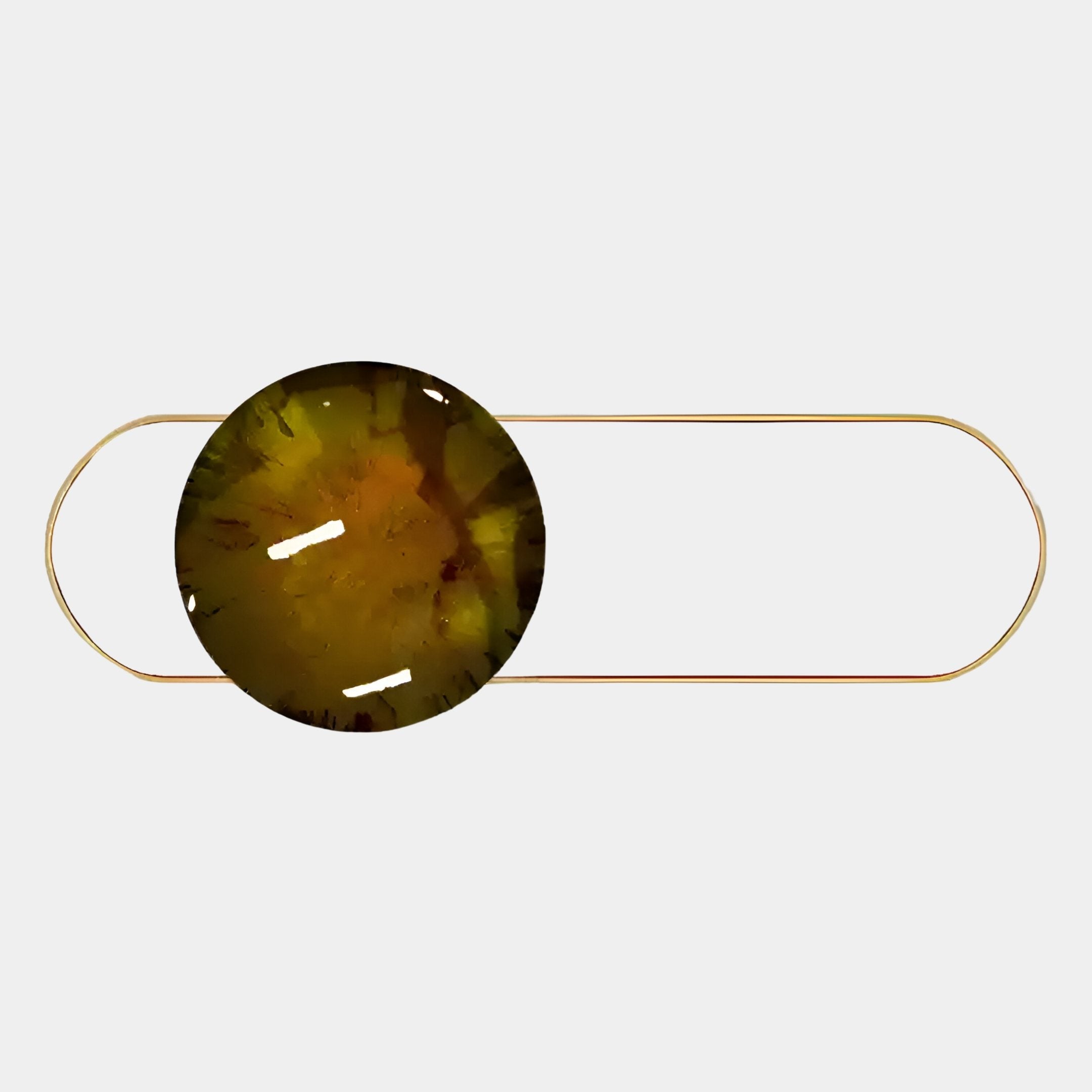 A minimalist hair barrette inspired by Giant Sculptures’ Vitreon 3D Amber Crystal Porcelain With Gold Frame Wall Art, featuring a round marbled resin centerpiece in brown and yellow on a thin gold oval frame.