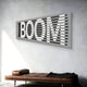 Angled view of modern wall art featuring the word BOOM illuminated through horizontal slats, adding a dynamic touch to contemporary interiors.