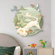 The Gaia Misty Pastel Wood Engraving 3D LED Wall Art by Giant Sculptures features a stylized deer with large antlers wrapped in abstract foliage and flowers, with birds perched on the antlers. Below, colorful toy figures and a star-patterned pillow rest on a bed, all in soothing pastel tones.