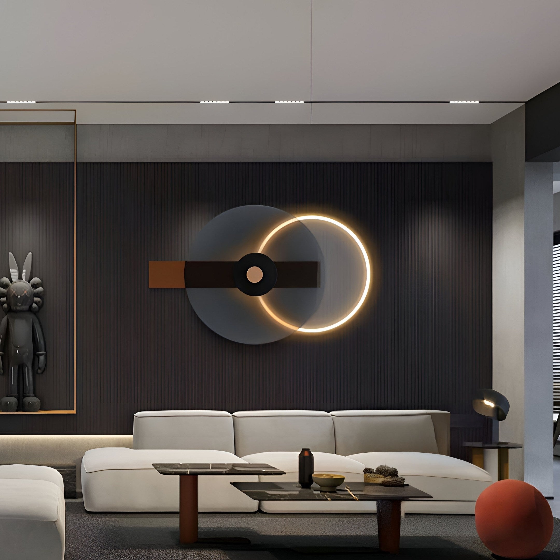 A modern living room with a minimalist design features a sectional sofa and dark wood coffee table. Contemporary wall art and circular lighting add flair. A sculpture stands in the corner, while Eclipse I Charcoal Bronze Acrylic 3D LED Wall Art by Giant Sculptures graces the neutral palette.