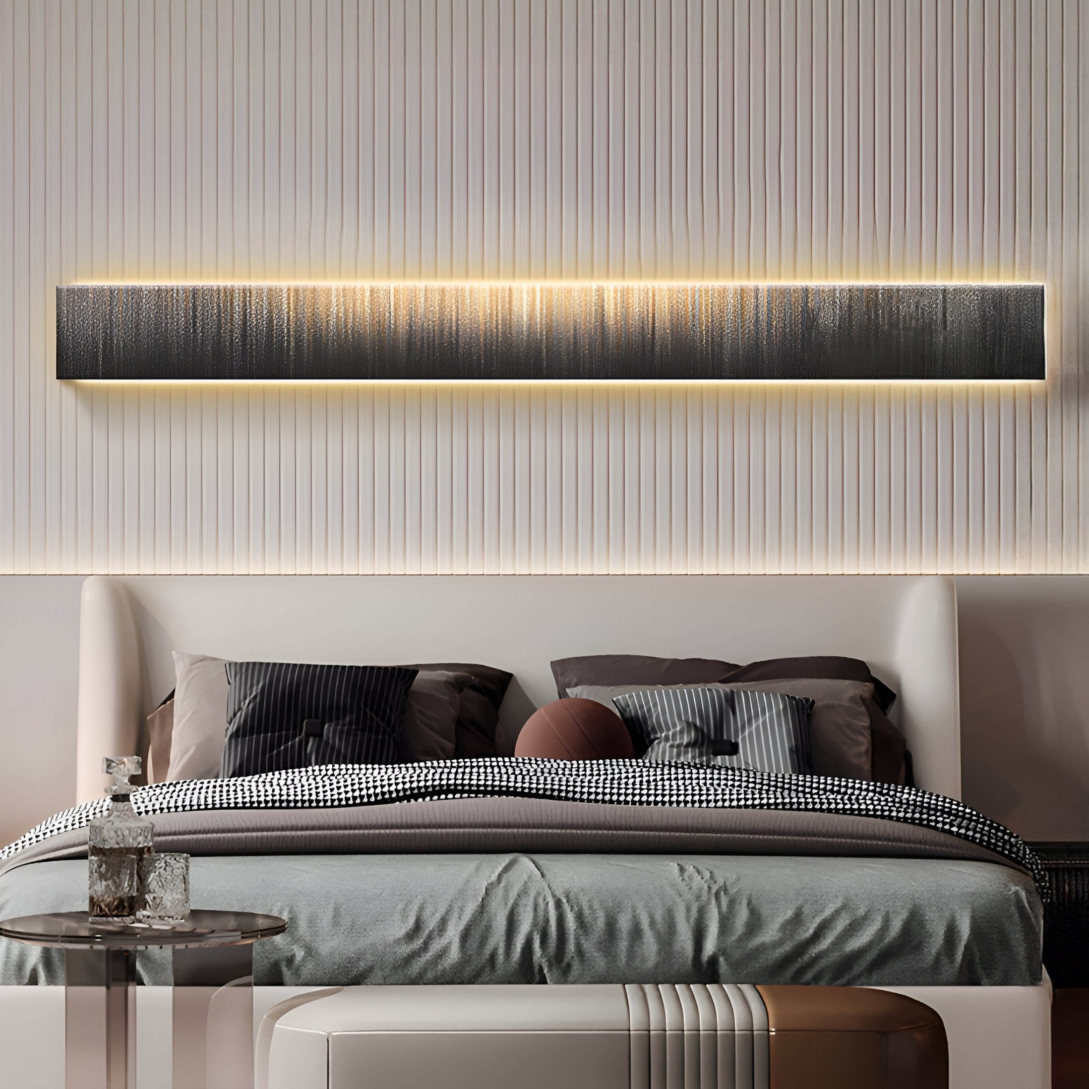 In a modern bedroom, the bed is neatly made with black, white, and gray bedding under the Radiance Bronze Luster Canvas LED Wall Art by Giant Sculptures. A glass side table complements the rooms décor.