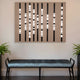 Above a light blue bench, the Strata Taupe LED Wall Art by Giant Sculptures with vertical black bars is illuminated. Two green potted plants sit beside the bench against a light wall, ideal for modern homes.