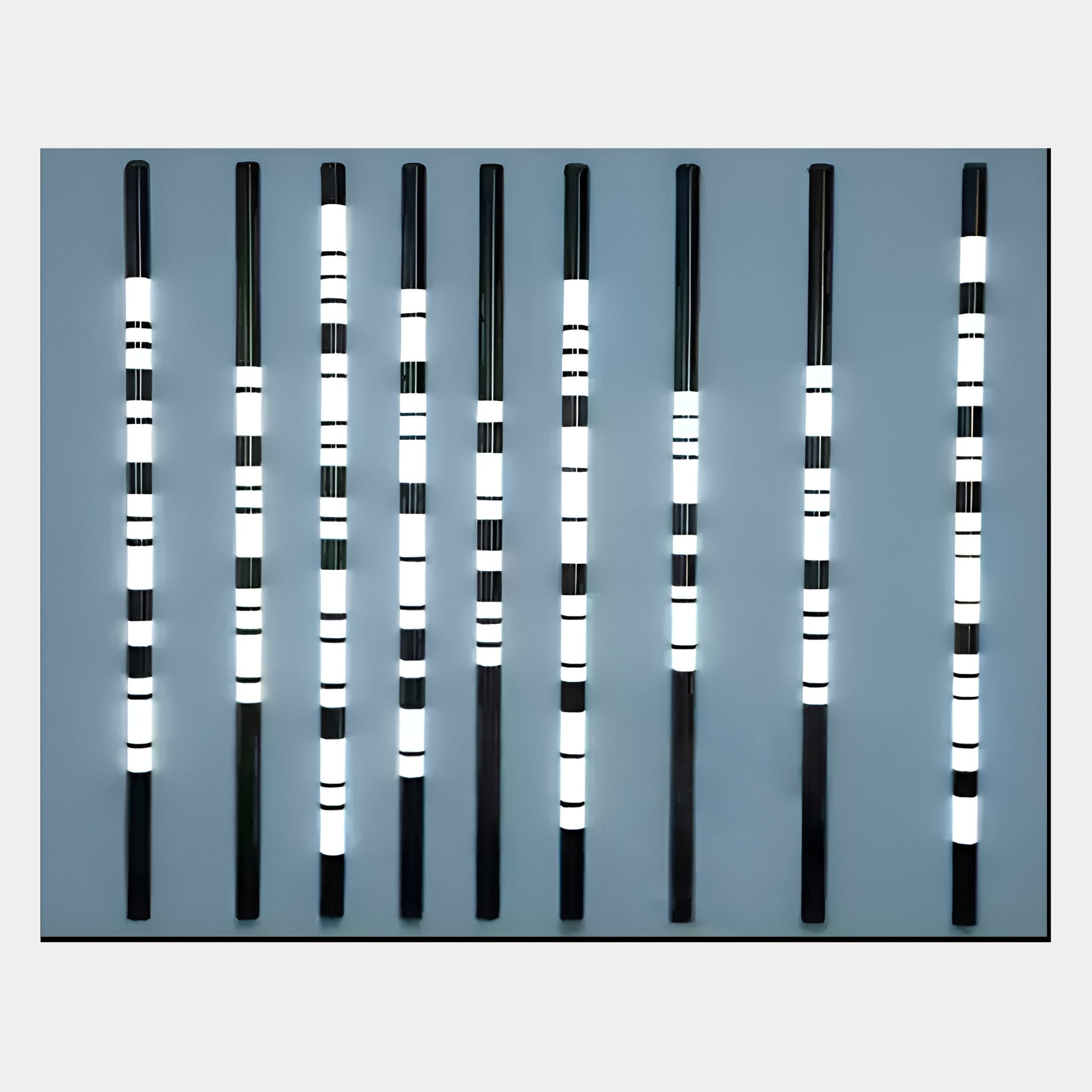 Strata Steel Blue LED Wall Art by Giant Sculptures features eight vertical black rods with evenly spaced white illuminated bands, creating a modern and symmetrical design ideal for contemporary spaces.