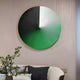 A chic living room radiates modern elegance with a round wall decoration in black, white, and green hues. Below it, a white couch adorned with black and gray cushions sits next to a table featuring the Orbit Emerald Hand-Painted Canvas 3D LED Wall Art by Giant Sculptures.