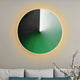 The Orbit Emerald Hand-Painted Canvas 3D LED Wall Art by Giant Sculptures features black, white, and green segments creating a warm gradient glow. Cotton branches in a vase beside a white sofa with teal cushions complete the modern elegant look.