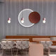 The restaurants modern decor showcases the Soluna Copper Acrylic 3D LED Wall Art by Giant Sculptures on a textured wall, featuring an integrated LED tube that complements elegant seating with hexagonal cushions and brown accents under distinctive pendant lights.