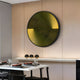 A modern dining room with a wooden wall showcases the Astral Gold Crystal Porcelain LED Wall Art by Giant Sculptures in yellow and black. Below, a table is set with glassware and red napkins. An aluminum frame holds three small black-and-white decorative spheres on a shelf above the table.