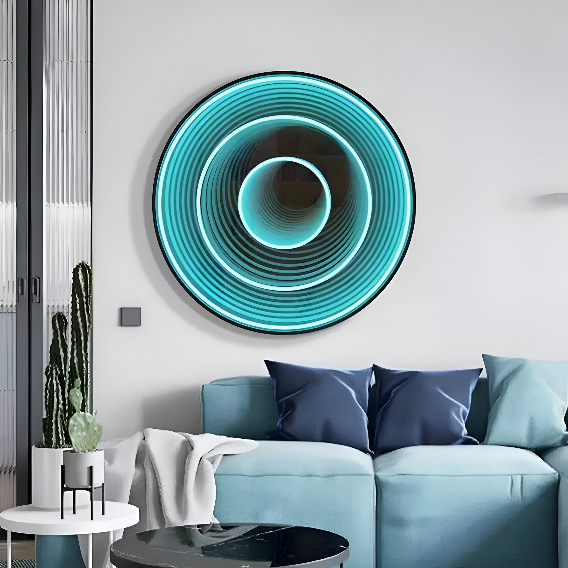 In a contemporary living room, a light blue sofa adorned with blue and white pillows is complemented by Giant Sculptures’ stunning Reflex Turquoise Mirror 3D LED Wall Art featuring concentric circles in blue and turquoise, while a tall plant enhances the natural vibe on the left.