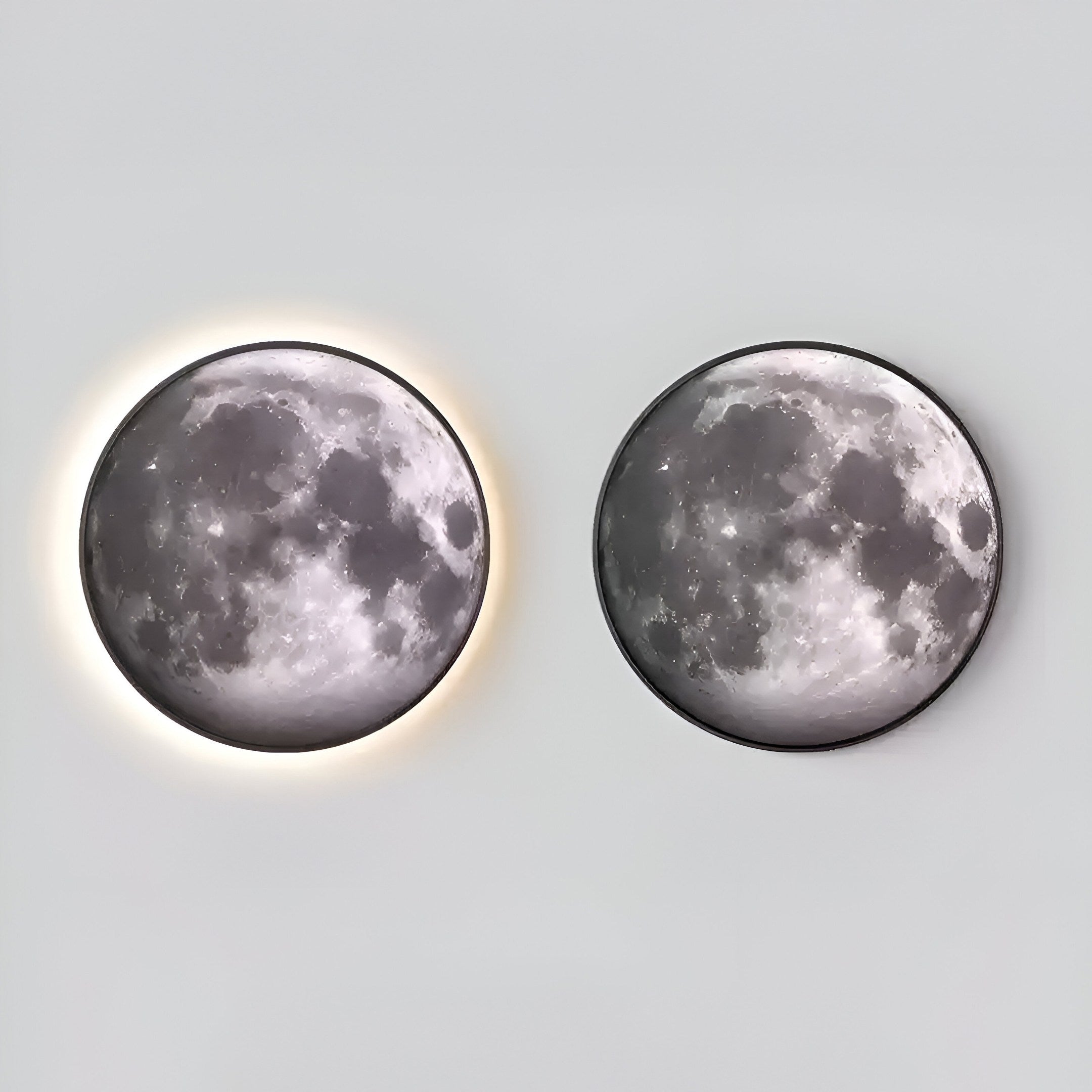 The Galaxia Moon Crystal Porcelain LED Wall Art by Giant Sculptures features two artistic lights inspired by the lunar surface— the left emits a soft halo while the right is dimmer, both detailed on a light gray background.