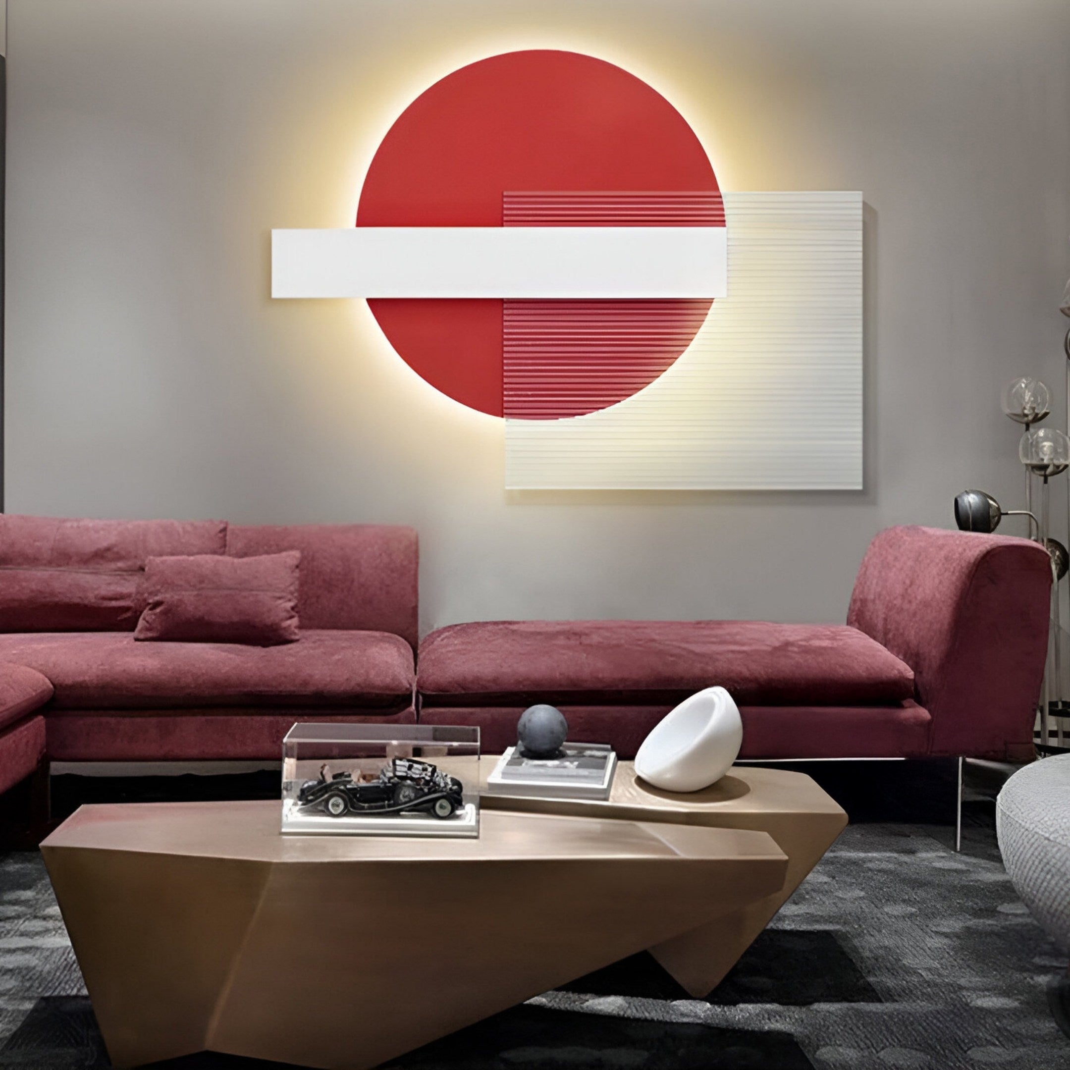 A modern living room showcases the Aeon Crimson Silk sectional sofa and Giant Sculptures Crimson Silk Leather 3D LED Wall Art featuring a red circle with white rectangles. A unique wooden coffee table displays decor, including a model car in a glass case, while neutral tones accent the space.