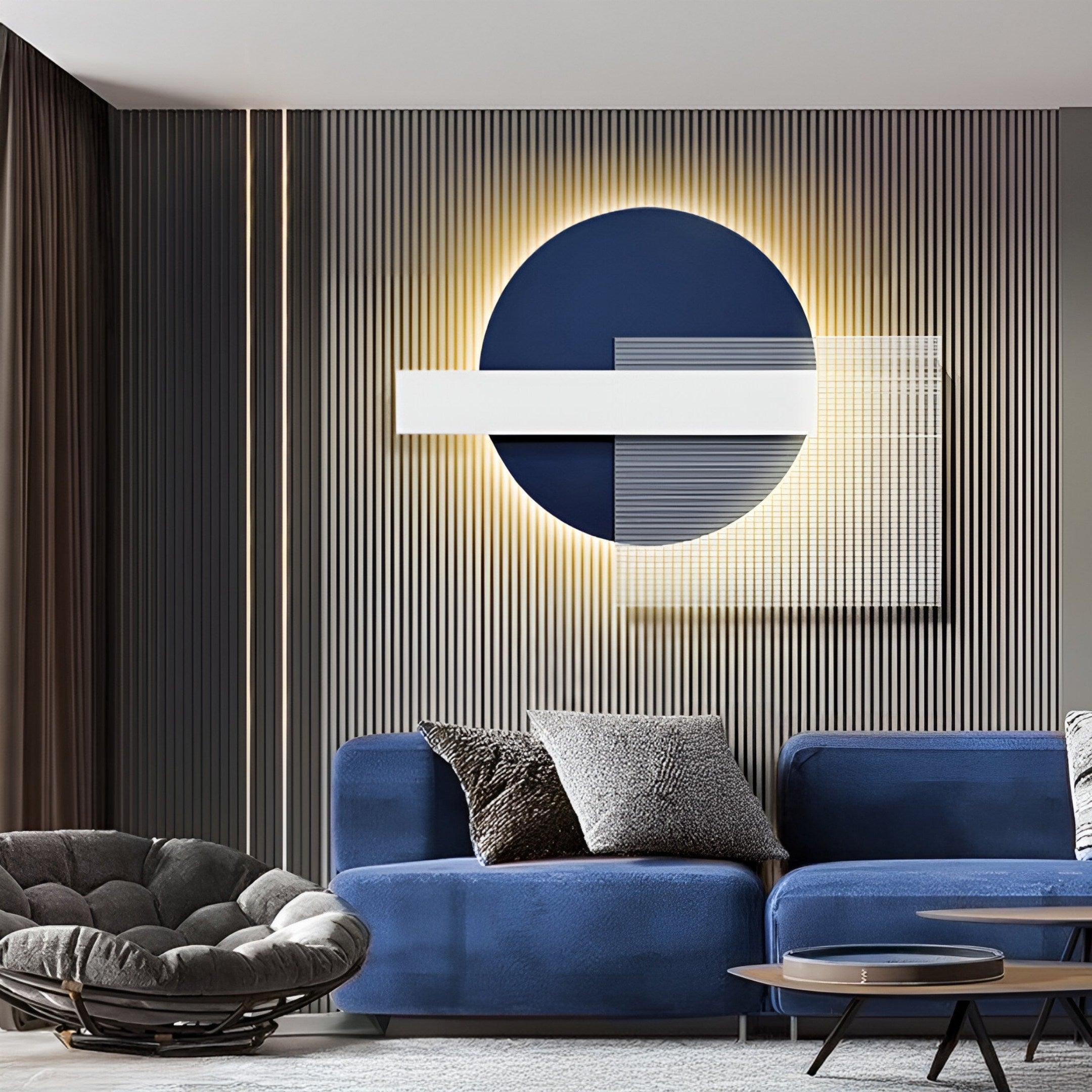 A modern living room features the Aeon Midnight Indigo Leather 3D LED Wall Art by Giant Sculptures. Against the wall, an indigo leather sofa sits with gray and black cushions. Nearby is a round, gray lounge chair, all set on a textured gray backdrop with warm lighting enhancing its contemporary look.