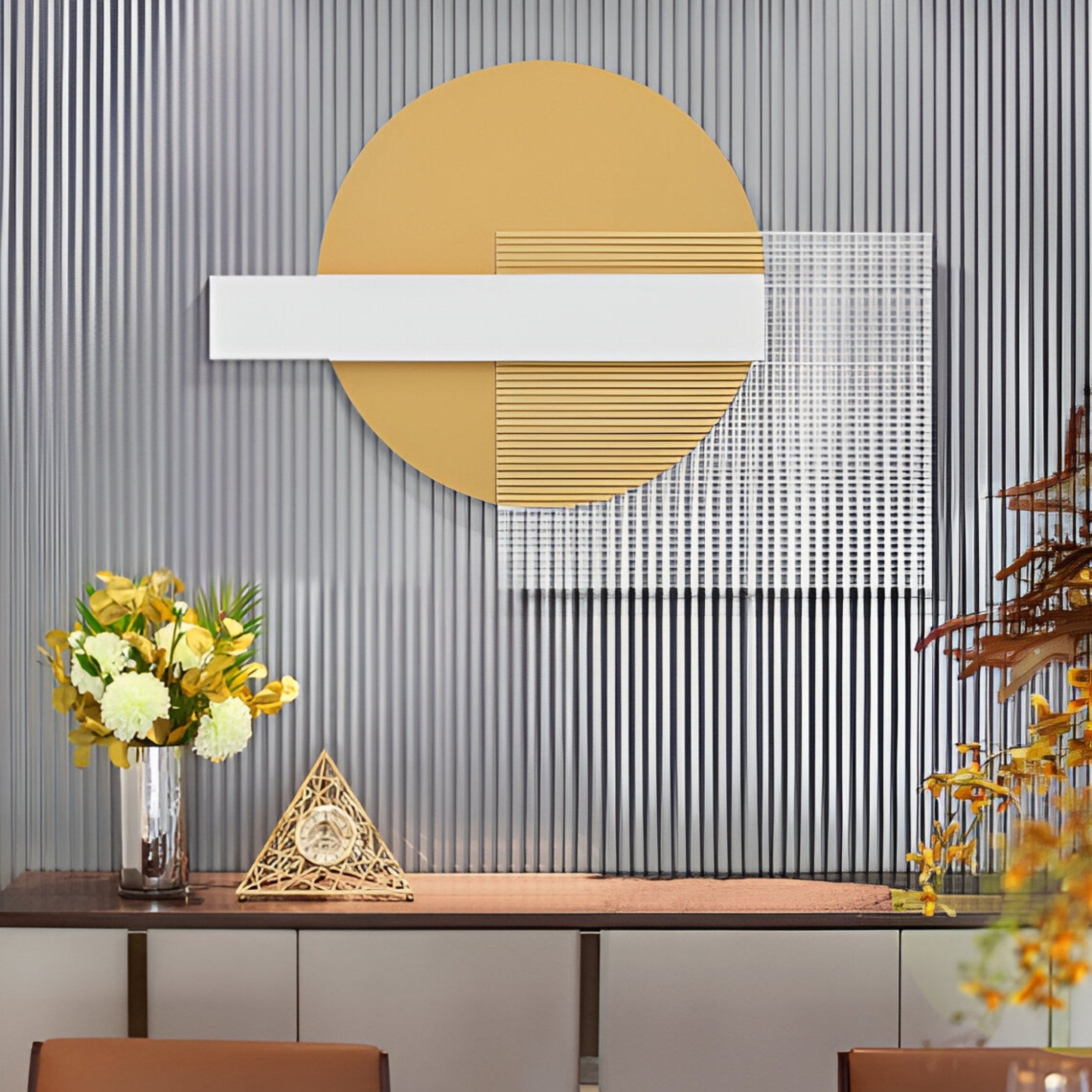 A modern decorative wall features Giant Sculptures Aeon Golden Sand Leather 3D LED Wall Art, showcasing geometric shapes: a large yellow circle, a white rectangle, and a textured square. Below is a table with Aeon Golden Sand flowers in a vase and a small triangular sculpture against vertical stripes.