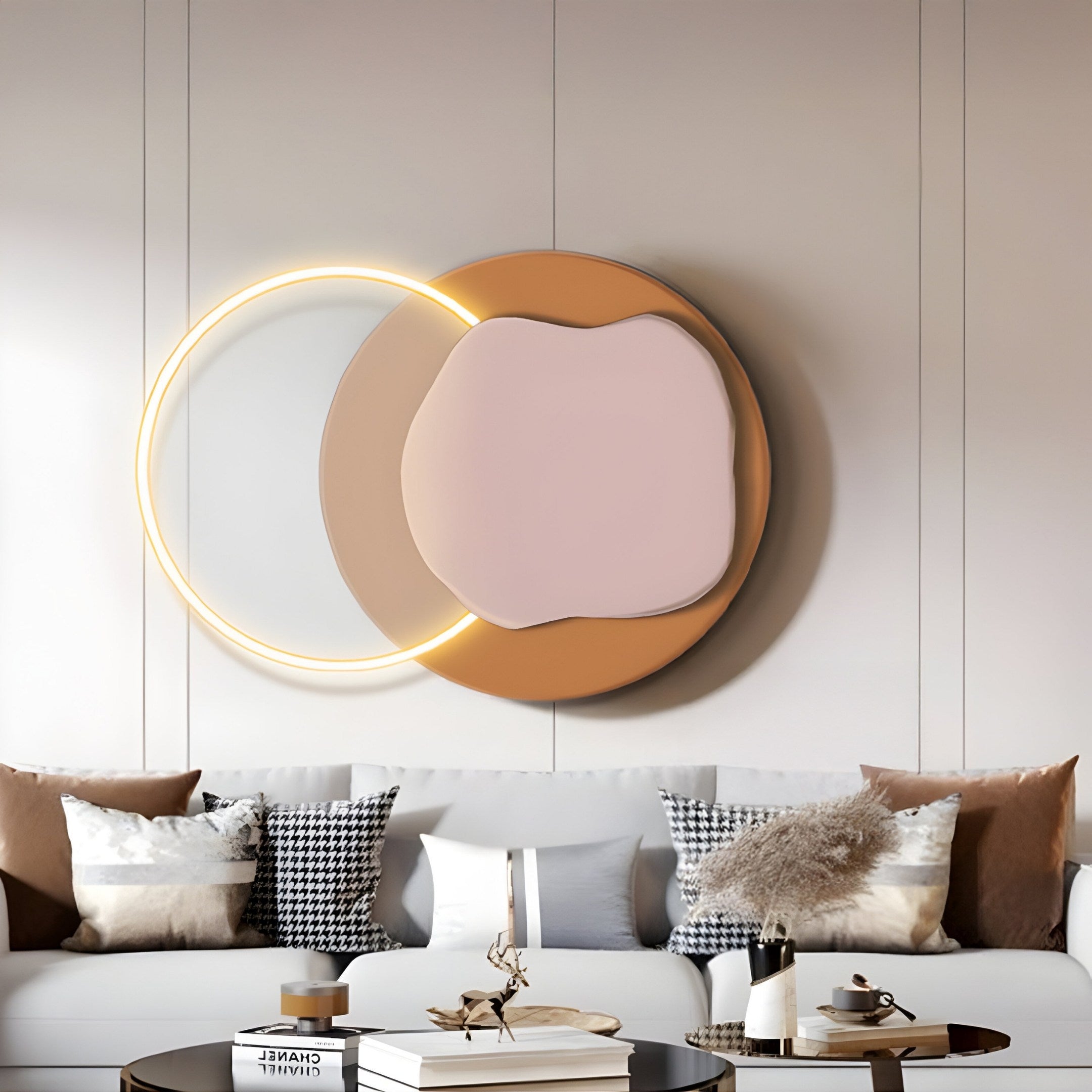 A modern living room showcases a plush white sofa with neutral cushions. Above, the Giant Sculptures Arcadia Rose Clay Leather 3D LED Wall Art features circular and organic shapes in peach, tan, and a glowing ring against light walls.