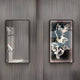 Two rectangular frames adorn a textured gray wall. The left displays the Horizon Butterfly Harmony 3D LED Mirror by Giant Sculptures, casting light on a white sculpture. The right features an abstract 3D art piece with swirling patterns and black accents, epitomizing modern decor.