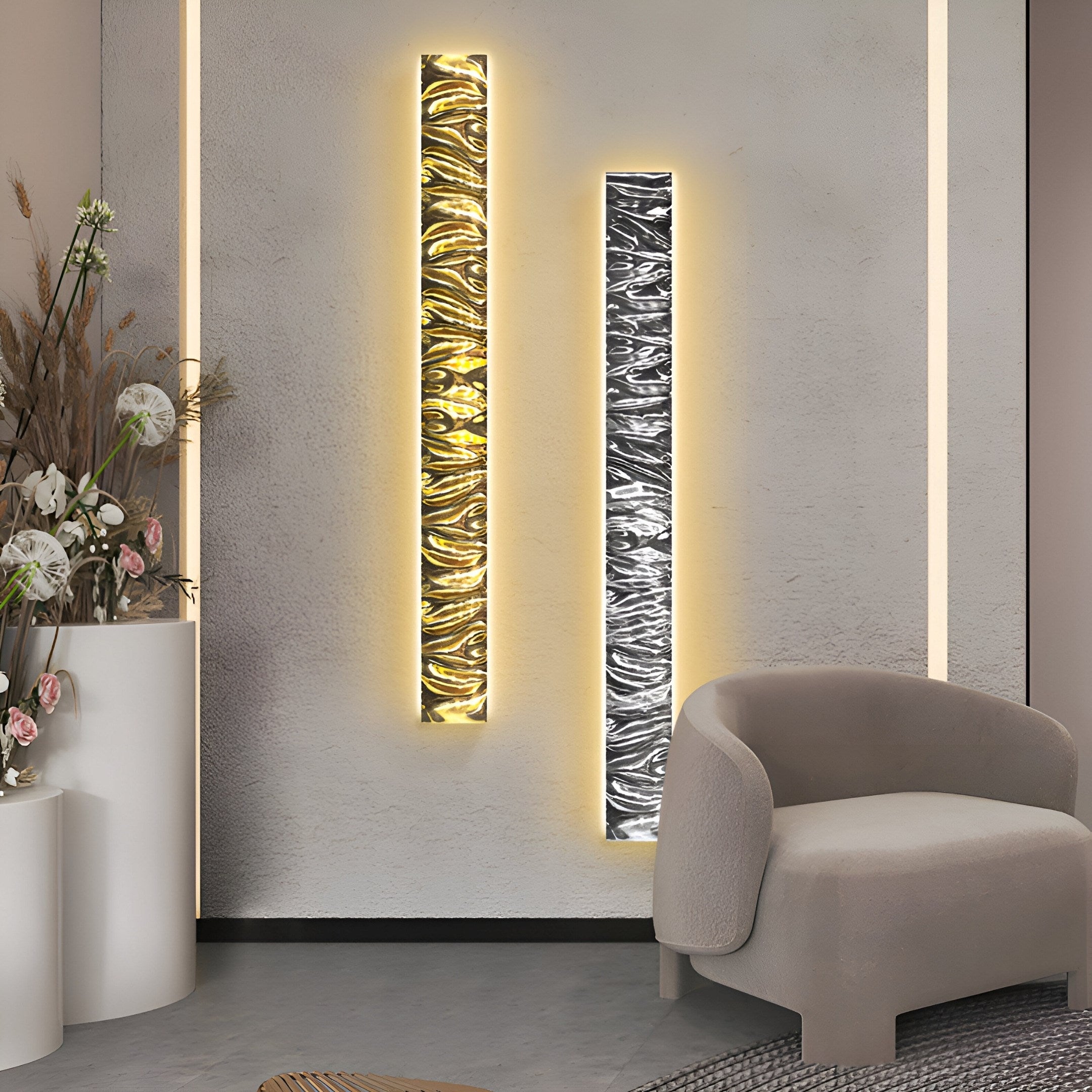 A modern interior showcases a Giant Sculptures gray armchair on the right, flanked by two Textura 3D Silver Leather Design Wall Art pieces featuring wavy geometric designs with warm backlighting, while a tall white planter with dried plants accents the left.