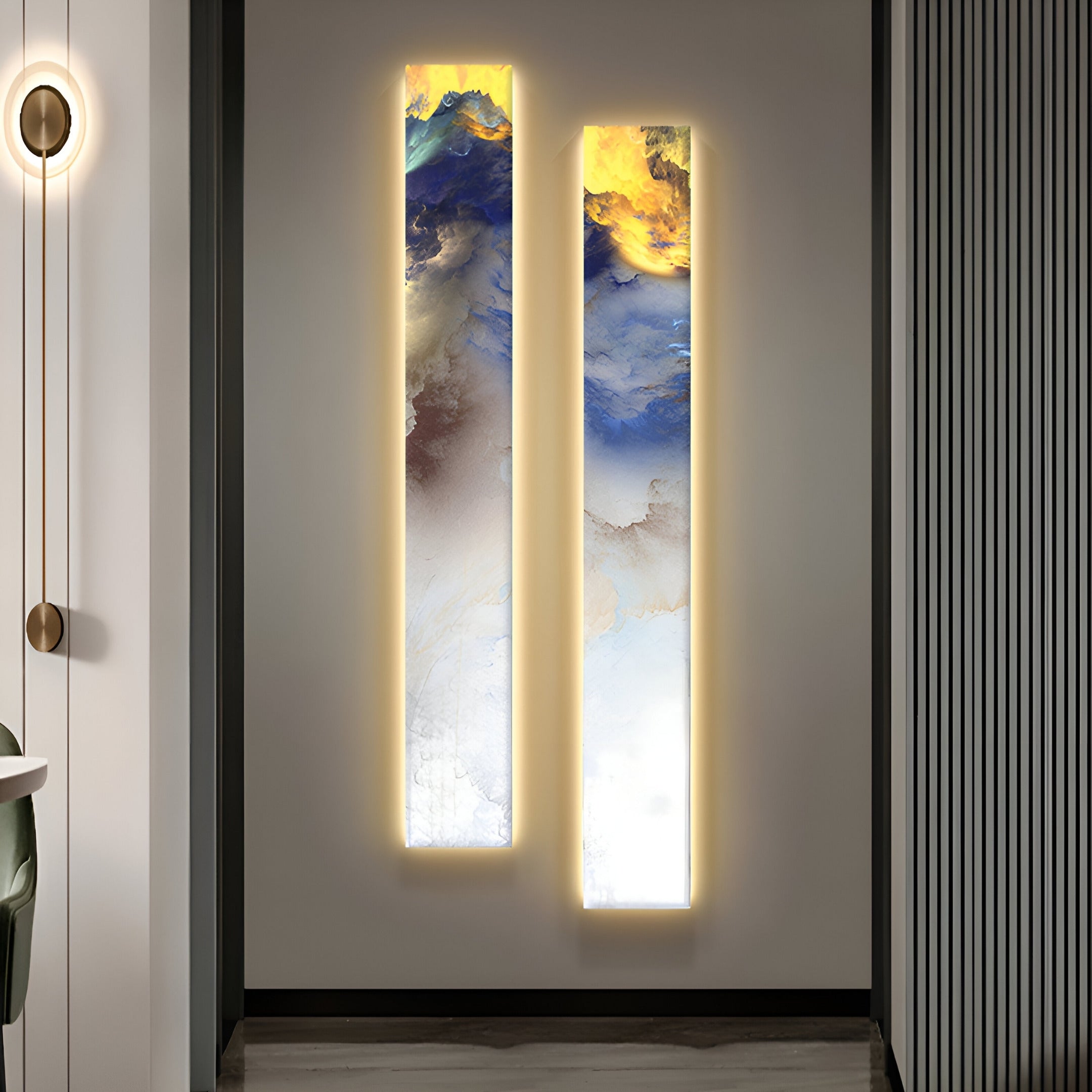 The Chroma White Ethereal Glow LED Wall Art Canvas by Giant Sculptures, a pair of vertical paintings in vibrant blue, gold, and white hues, elegantly illuminates a minimalist space featuring modern interiors with a round table and sleek vertical-striped panel.