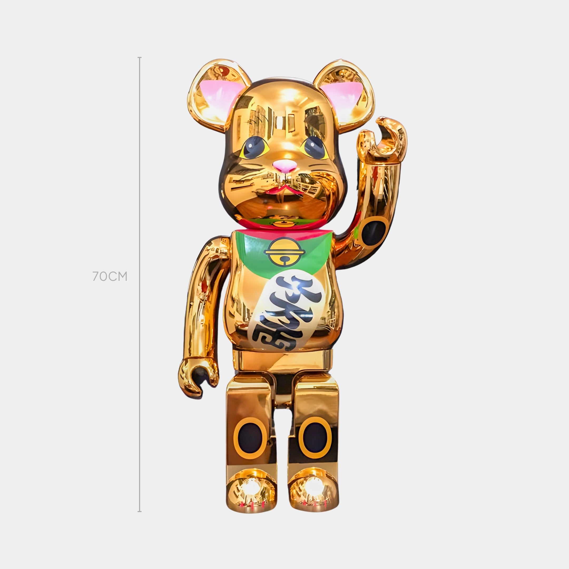 The Lucky Paw Gold Bear Sculpture - 70cm by Giant Sculptures features an electro-plated gold chrome finish, black details, red nose, and a green and white bib with Japanese characters in a maneki-neko style. Stands upright with right paw raised.