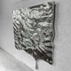 Lumineris Silver Melted Wave Metal 3D Wall Art in mirror-polished stainless steel, wall-mounted with a drip extending below, shown against a plain grey wall.