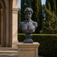 Large Classical David Bust Bronze Bust, 80cm, on a pedestal in a colonnaded courtyard with hedges and cypress trees in the background.