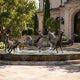 Large Traditional Running Deer Herd Bronze Fountain by Giant Sculptures with antique patina stags and does mid-leap in a stone basin outside a villa entrance.