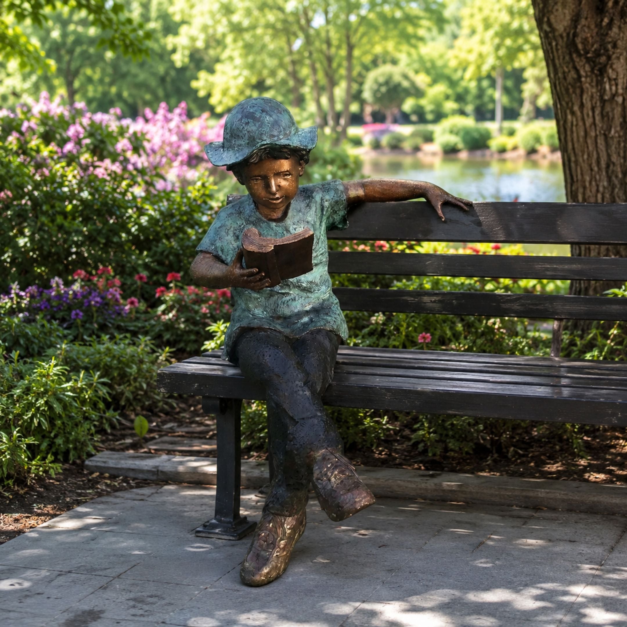 Life-Size Boy Reading on Bench Bronze Sculpture, 150cm, seated with ankles crossed and arm resting on the bench, set outdoors near a garden path.