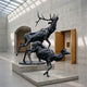 Life-Size Bugling Stag and Deer Bronze Sculpture by Giant Sculptures, dark patinated bronze pair mid-bugle and leaping on a pale plinth in a skylit gallery.