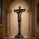Life-Size Classical Crucifixion of Christ Bronze Sculpture, 300cm, dark bronze finish on a rocky base, displayed in an arched stone church niche.