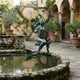 Life-Size Classical Mermaid and Merboy Bronze Sculpture by Giant Sculptures with green verdigris patina, set on a stone fountain in an Italianate courtyard.