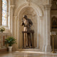 Life-Size Classical Saint Joseph the Worker Bronze Sculpture by Giant Sculptures, shown at a carpenter's workbench with mallet raised inside a stone chapel niche.