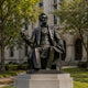 Giant Sculptures Life-Size Classical Seated Figure Bronze Statue, 250cm, seated on a carved chair with quill raised, on a stone plinth outside a stone building.