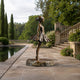 Life-Size Contemporary Ballerina Bronze Sculpture, 190cm, on a stone base beside a garden pool with balustrade stairs and greenery.