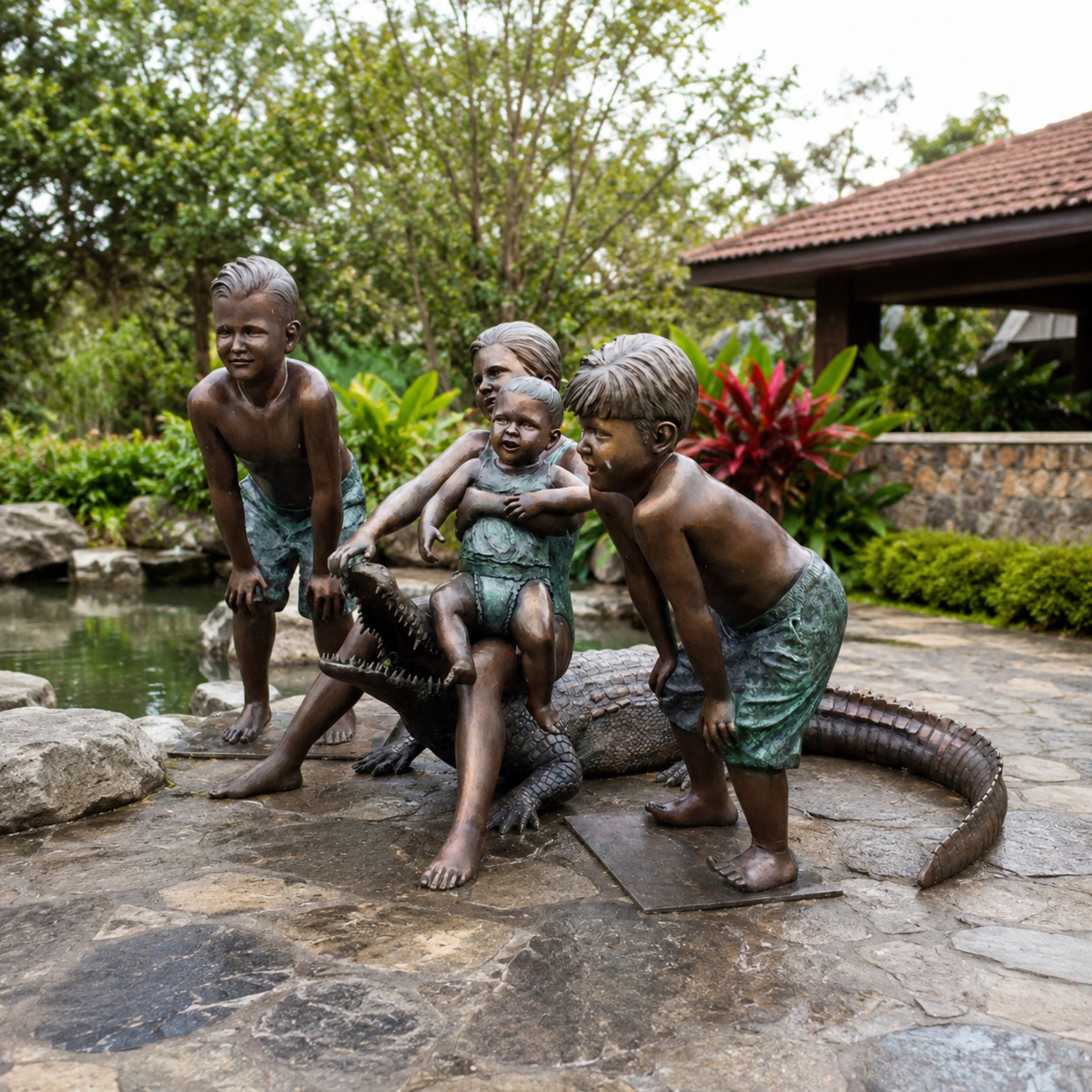 Life-Size Contemporary Children and Crocodile Bronze Sculpture, 150cm, showing four children playing on a bronze crocodile beside a garden pond.