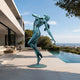 Life-Size Contemporary Dancing Nude Female Bronze Sculpture in verdigris green, arching backward on tiptoe, on a poolside terrace with ocean view.