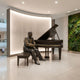 Life-Size Contemporary Seated Pianist and Grand Piano Bronze Sculpture by Giant Sculptures displayed in a modern lobby beside a soundwave wall and green moss art.