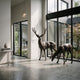 Life-Size Standing Stag and Grazing Doe Bronze Sculpture by Giant Sculptures displayed in a bright modern atrium beside floor-to-ceiling windows and a garden.